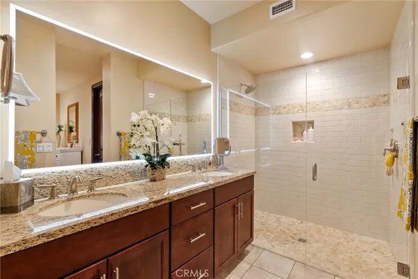 a bathroom with a granite countertop sink a mirror and a shower
