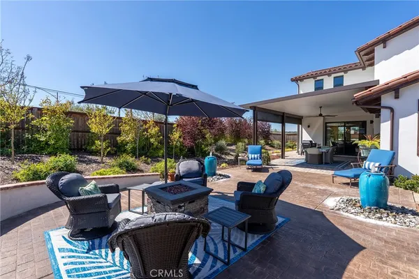 a view of a patio with couches table and chairs under an umbrella with a fire pit