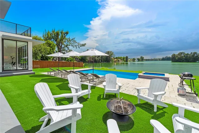 a view of a backyard with lawn chairs under an umbrella