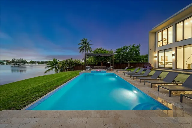 a view of a swimming pool with lounge chairs in front of house