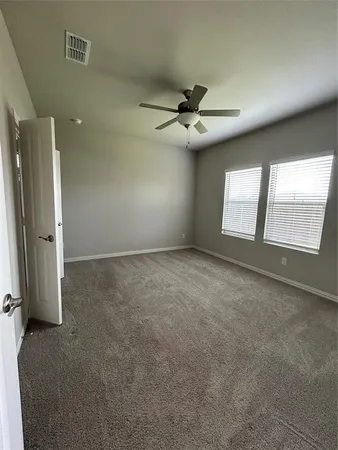 an empty room with windows and fan