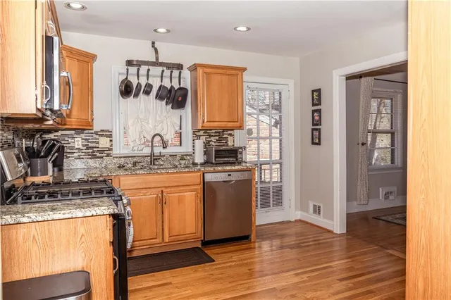 a kitchen with stainless steel appliances granite countertop a stove a sink and a refrigerator
