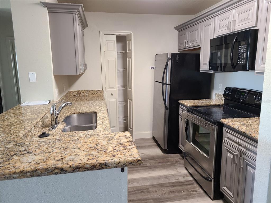 8911 Manor Loop, Unit 205 Lakewood Ranch, FL 34202 - Photo 17 of 33 a kitchen with stainless steel appliances granite countertop a refrigerator a stove a sink and a microwave
