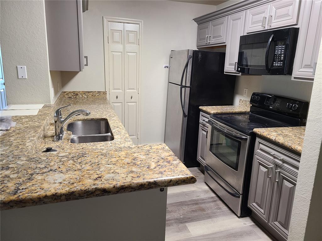 8911 Manor Loop, Unit 205 Lakewood Ranch, FL 34202 - Photo 3 of 33 a kitchen with granite countertop a sink stove and refrigerator