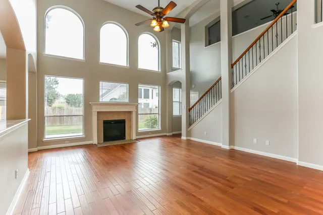 a view of an empty room with wooden floor fireplace and a window