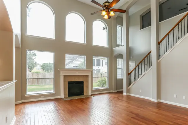 an empty room with wooden floor a fireplace and windows