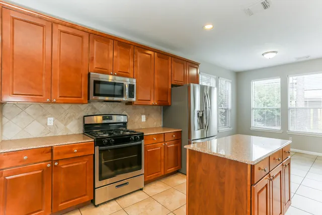 a kitchen with stainless steel appliances granite countertop a stove a sink dishwasher a refrigerator and a microwave
