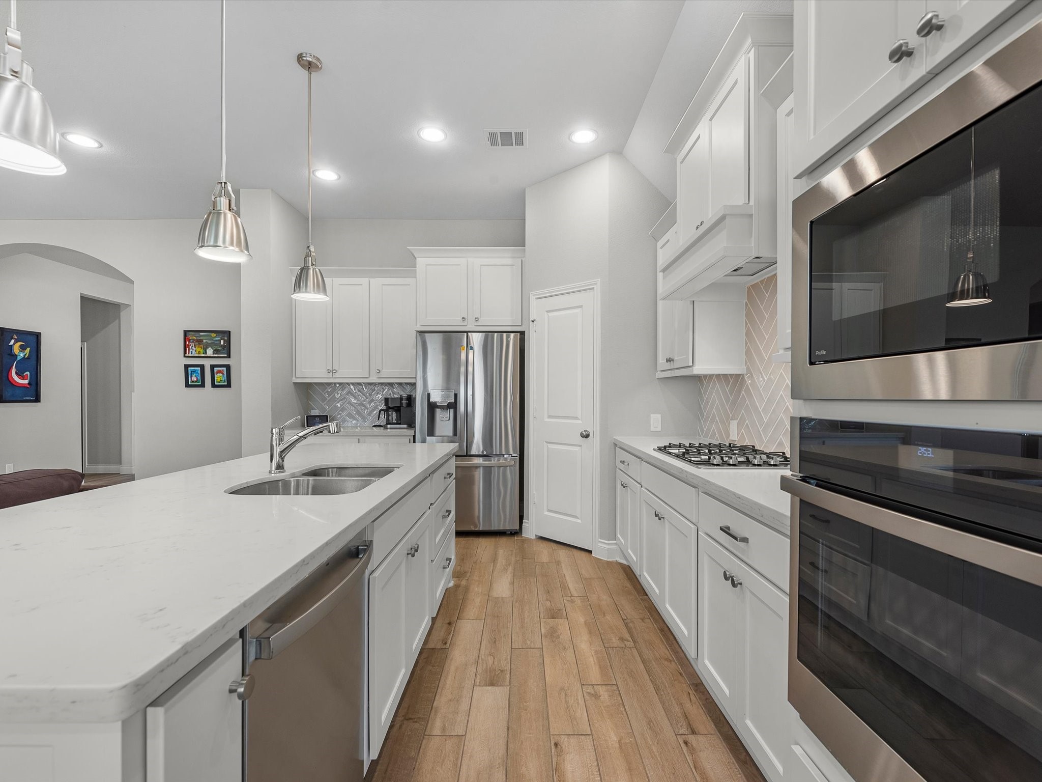 10135 Napier Drive Rosharon, TX 77583 - Photo 6 of 36 Bright, neutral kitchen featuring white cabinetry, sleek white countertops, and a stylish gray herringbone backsplash.