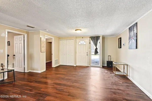 a view of an empty room with wooden floor and windows