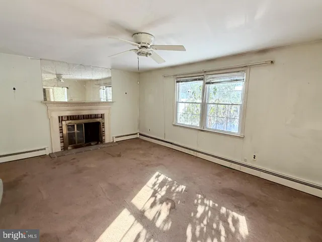 an empty room with windows and fireplace