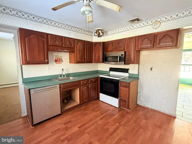 a kitchen with stainless steel appliances granite countertop a sink a stove a refrigerator cabinets and wooden floor
