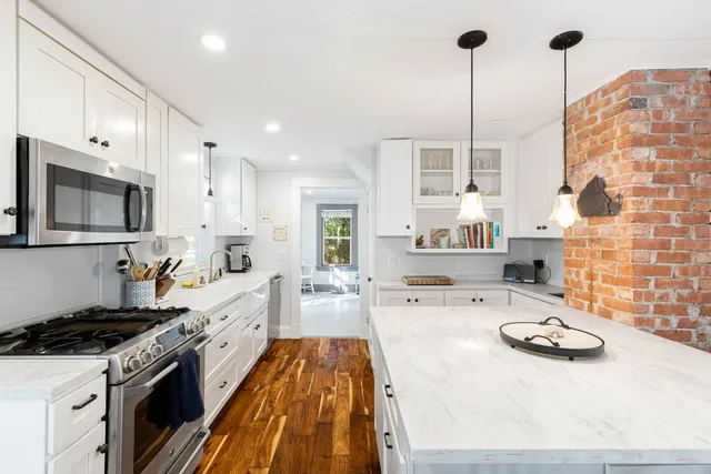 a large kitchen with stainless steel appliances a stove a sink dishwasher and a fireplace with wooden floor