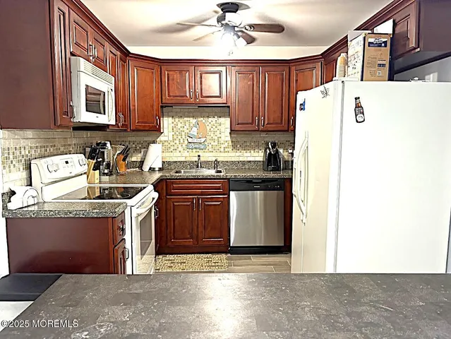 a kitchen with stainless steel appliances granite countertop a refrigerator a stove a sink dishwasher and a microwave oven