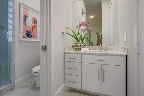 a bathroom with a granite countertop sink vanity mirror and toilet