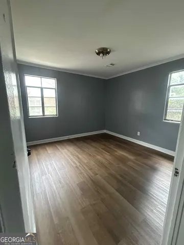 an empty room with wooden floor and windows