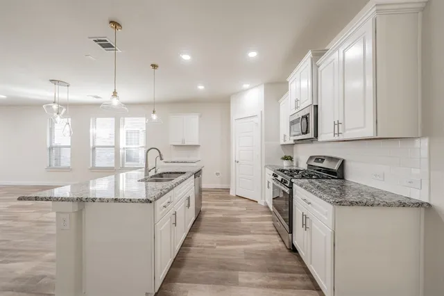 a large kitchen with stainless steel appliances granite countertop a stove sink and cabinets