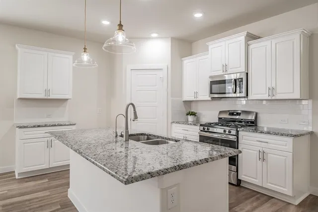 a kitchen with stainless steel appliances granite countertop a sink stove and cabinets