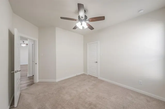 a view of an empty room and chandelier fan