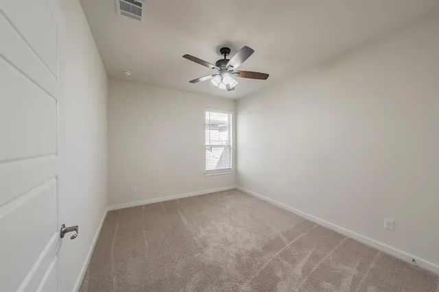 an empty room with a window and a fan