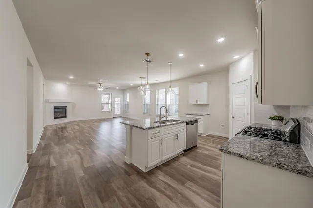 a kitchen with stainless steel appliances granite countertop a stove and a wooden floors