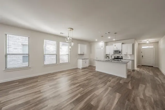 a view of an empty room with window and wooden floor