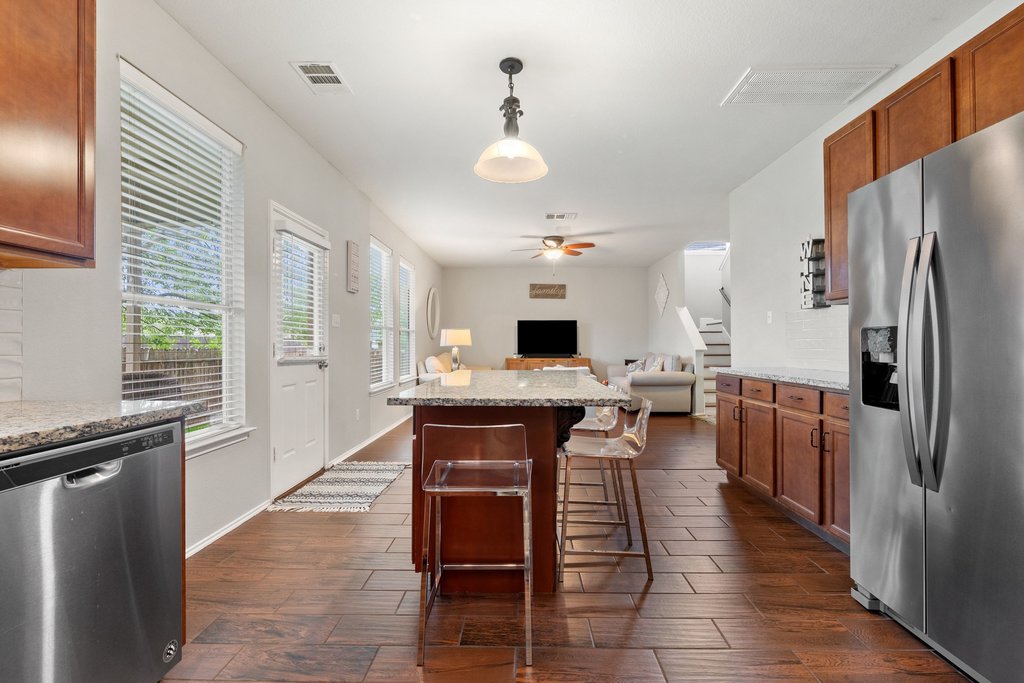 140 Wolfberry Path Buda, TX 78610 - Photo 13 of 35 a kitchen with stainless steel appliances granite countertop a refrigerator a sink dishwasher a dining table and chairs with wooden floor