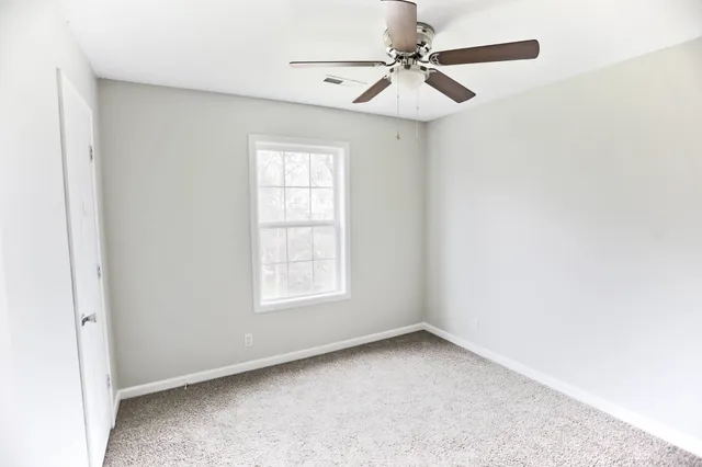 an empty room with a window and a fan