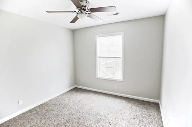 an empty room with a window and a fan