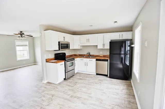 a kitchen with a refrigerator a stove top oven and white cabinets