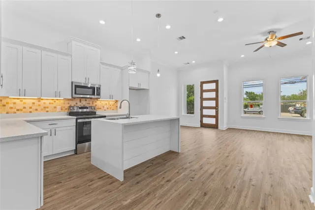 a kitchen with white cabinets and window