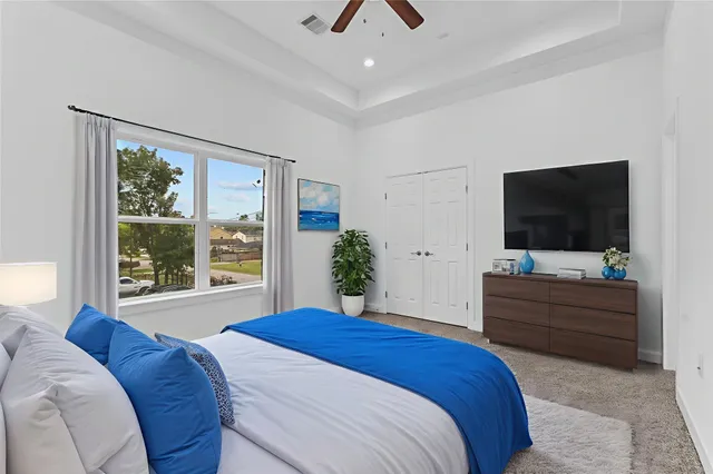 a spacious bedroom with a bed and a flat screen tv