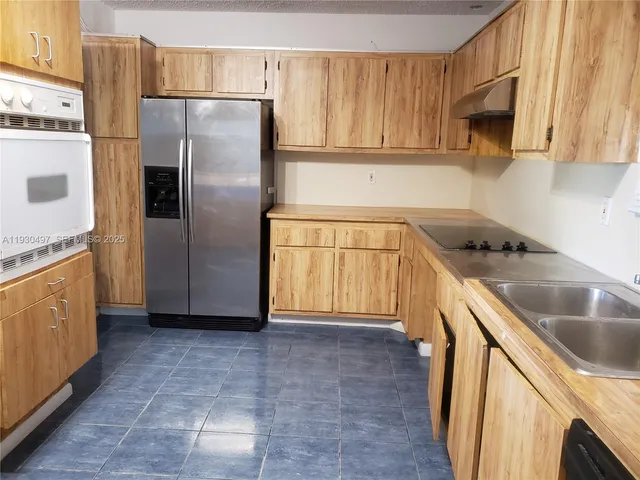 a kitchen with a refrigerator sink and cabinets