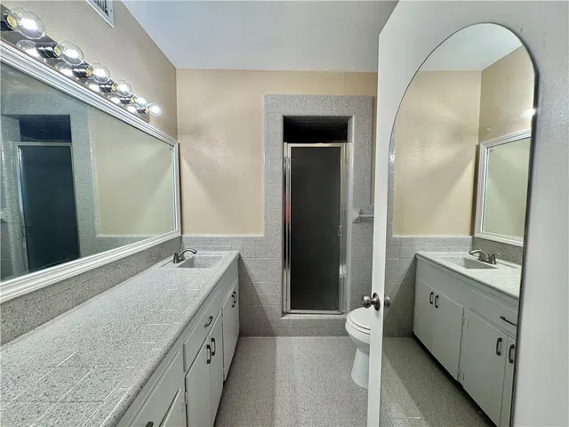 a spacious bathroom with a granite countertop sink a toilet a large mirror and a shower
