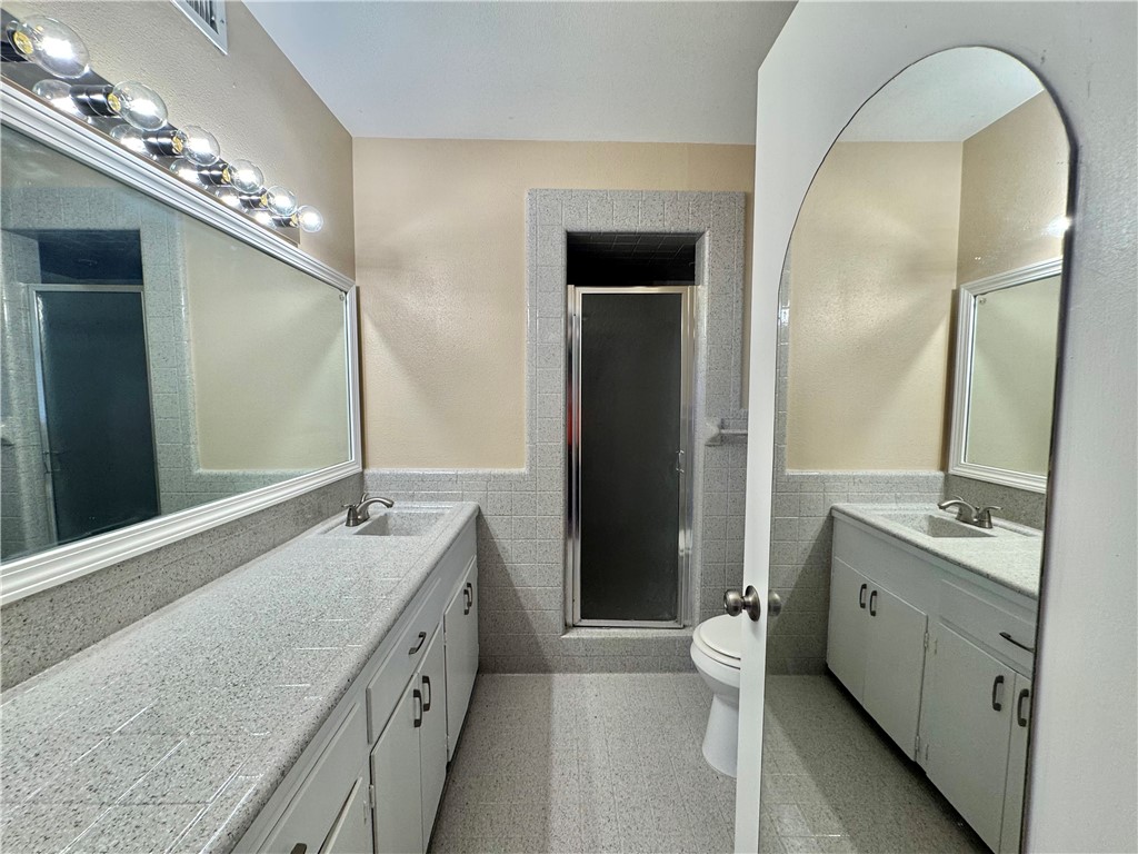 614 Dolphin Place Corpus Christi, TX 78411 - Photo 17 of 23 a spacious bathroom with a granite countertop sink a toilet a large mirror and a shower
