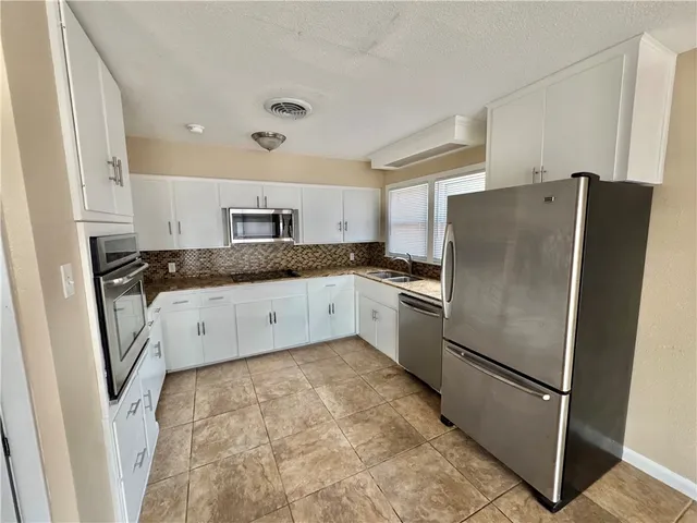 a kitchen with granite countertop a refrigerator sink and cabinets