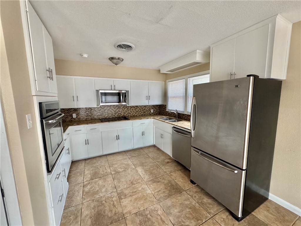 614 Dolphin Place Corpus Christi, TX 78411 - Photo 7 of 23 a kitchen with granite countertop a refrigerator sink and cabinets