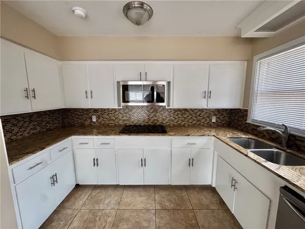 a kitchen with granite countertop white cabinets and stainless steel appliances