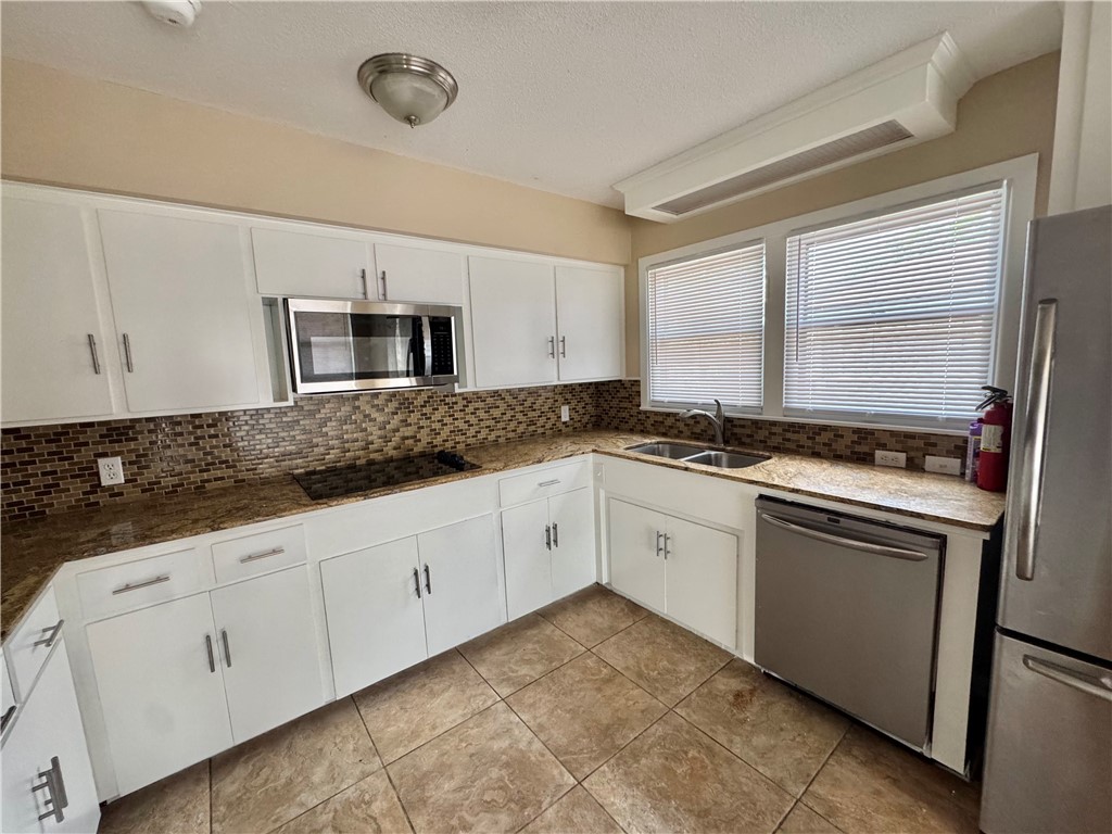 614 Dolphin Place Corpus Christi, TX 78411 - Photo 9 of 23 a kitchen with granite countertop white cabinets white stainless steel appliances with a sink and dishwasher