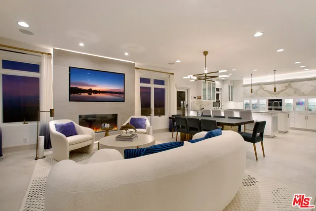 a living room with furniture kitchen view and a flat screen tv