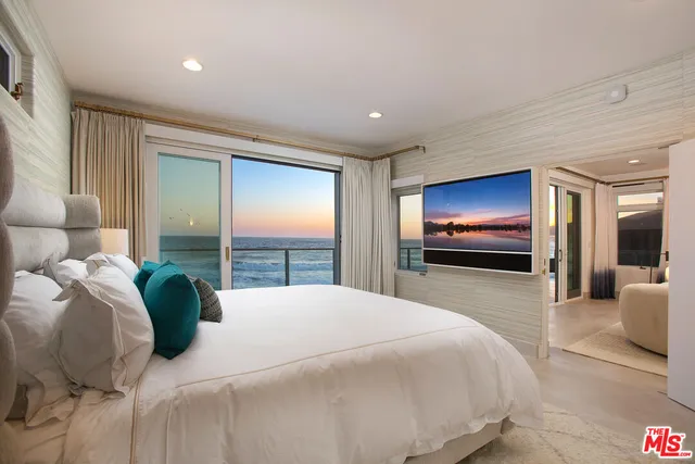 a bedroom with a bed and large windows