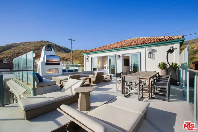 a view of a roof deck with table and chairs a barbeque with wooden floor and fence