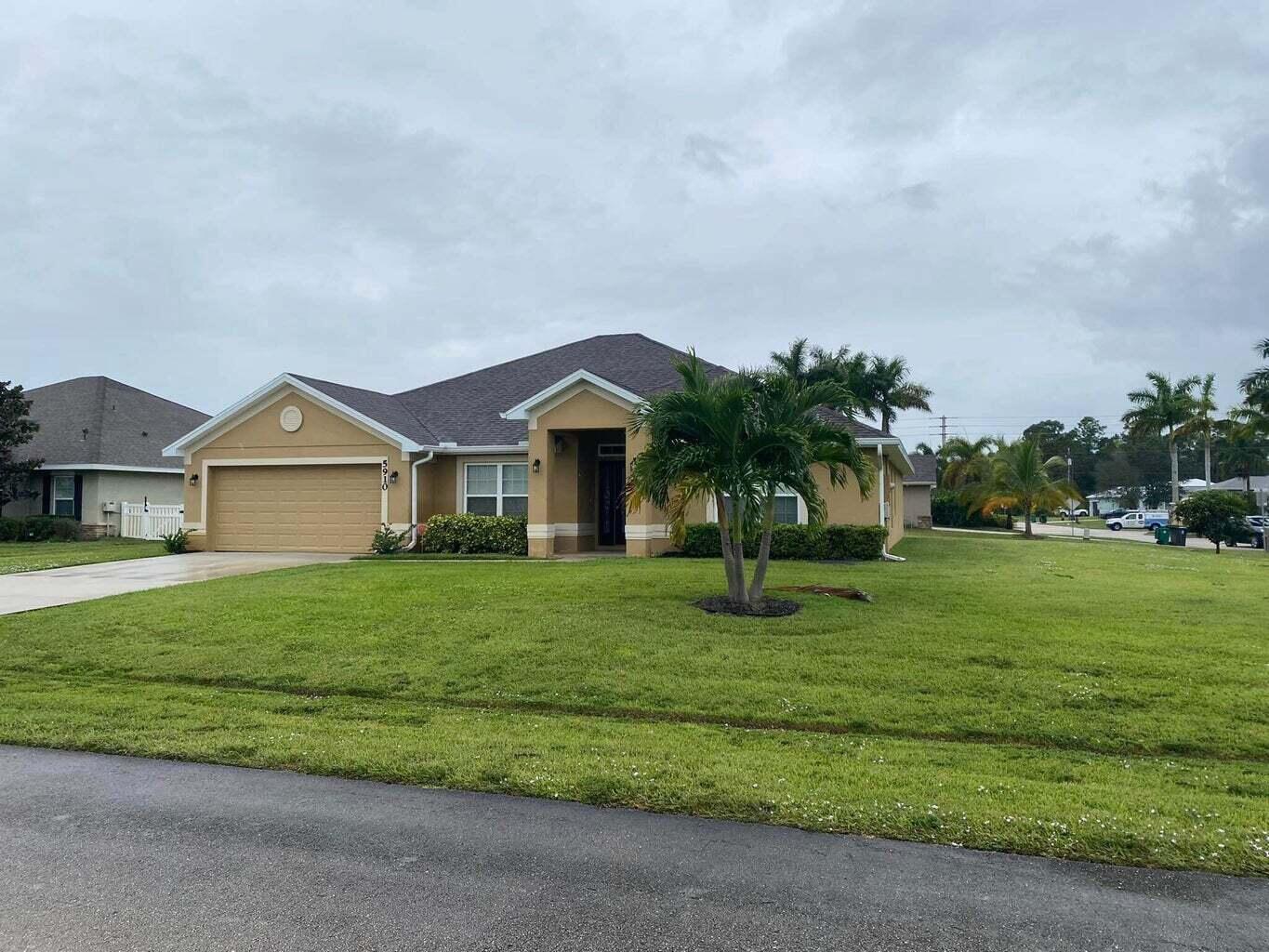 5910 Northwest Java Court Port St. Lucie, FL 34986 - Photo 1 of 16 a front view of a house with a yard and trees