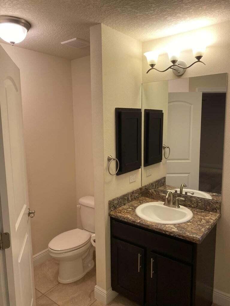 5910 Northwest Java Court Port St. Lucie, FL 34986 - Photo 11 of 16 a bathroom with a granite countertop sink toilet and a mirror