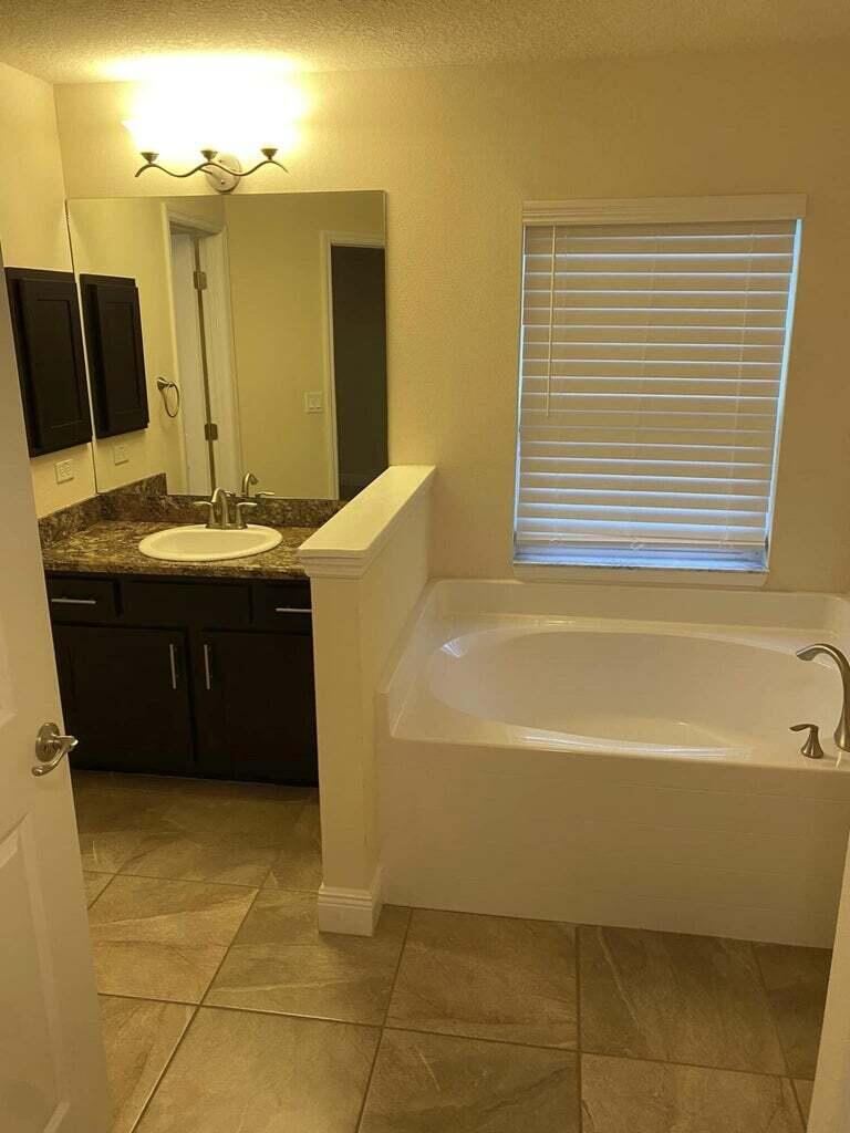 5910 Northwest Java Court Port St. Lucie, FL 34986 - Photo 13 of 16 a bathroom with a tub sink and mirror