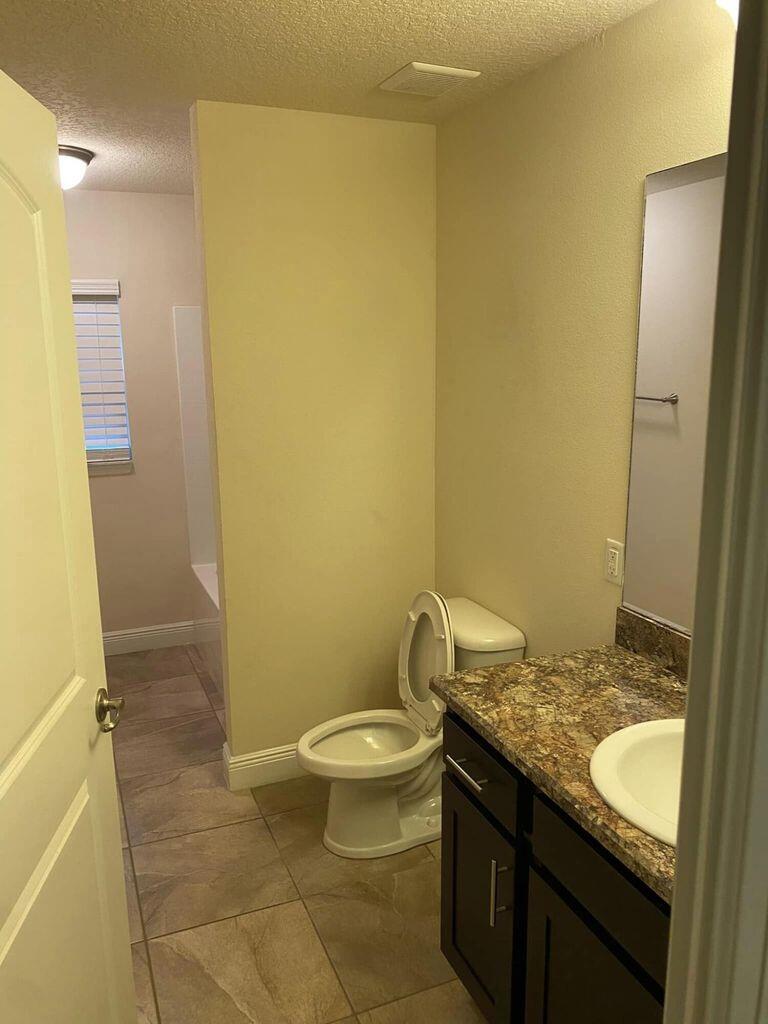 5910 Northwest Java Court Port St. Lucie, FL 34986 - Photo 15 of 16 a bathroom with a granite countertop sink toilet and shower
