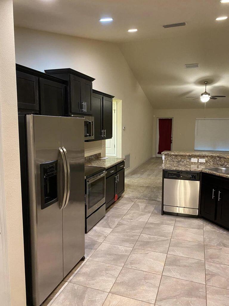 5910 Northwest Java Court Port St. Lucie, FL 34986 - Photo 5 of 16 a kitchen with stainless steel appliances granite countertop a refrigerator and a stove
