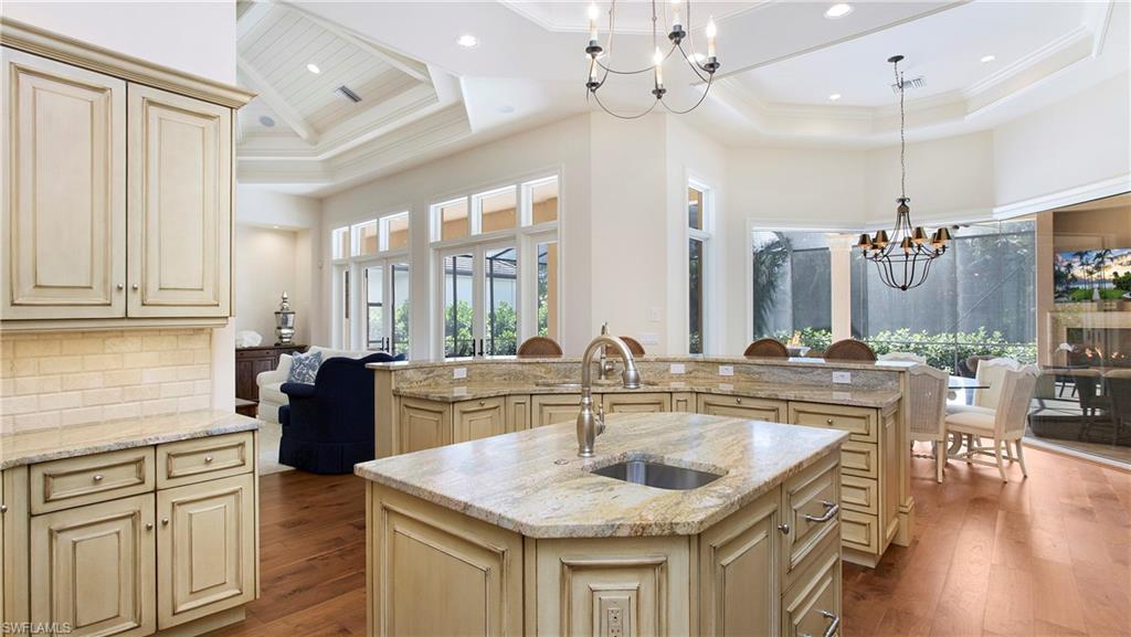645 Rudder Road Naples, FL 34102 - Photo 13 of 45 a kitchen with a stove a refrigerator a sink dishwasher a dining table and chairs with wooden floor