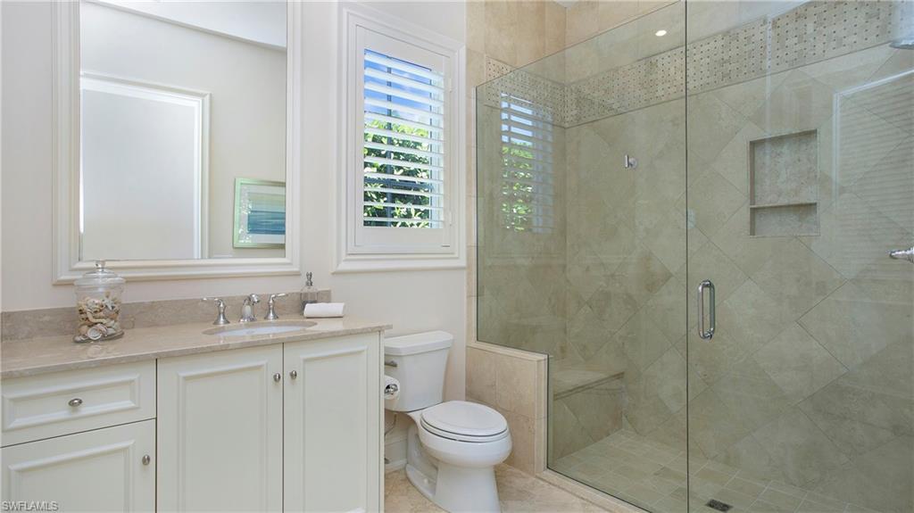 645 Rudder Road Naples, FL 34102 - Photo 32 of 45 a bathroom with a granite countertop toilet a sink and a shower