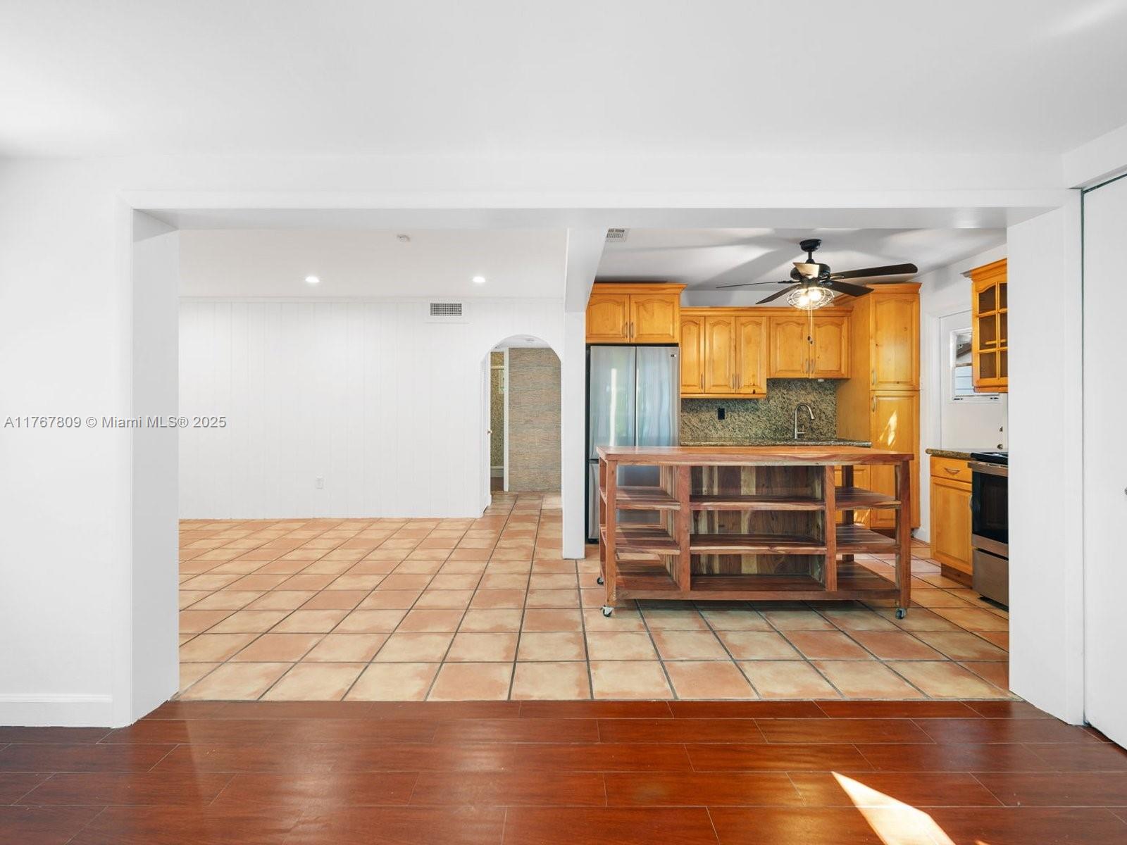3631 Loquat Avenue Miami, FL 33133 - Photo 13 of 31 a view of empty room with wooden floor and kitchen view