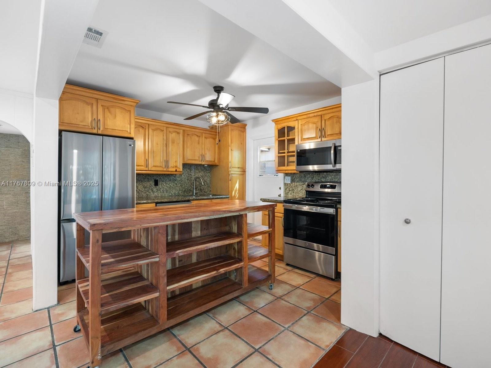 3631 Loquat Avenue Miami, FL 33133 - Photo 14 of 31 a kitchen with stainless steel appliances a stove and more cabinets